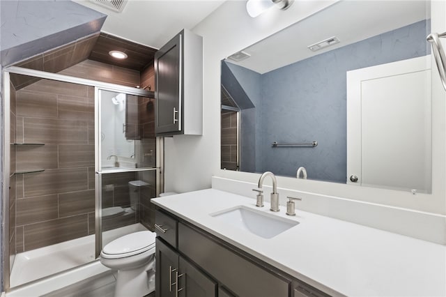 bathroom with vanity, a shower with shower door, and toilet