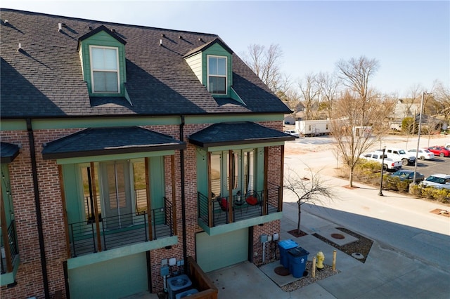 exterior space with a shingled roof and brick siding