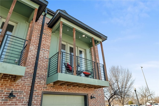 view of side of property featuring a balcony, a garage, and brick siding