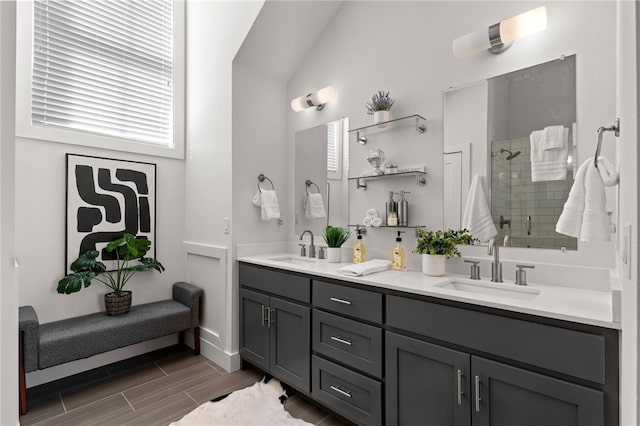 full bath featuring vaulted ceiling, double vanity, a sink, and a shower stall