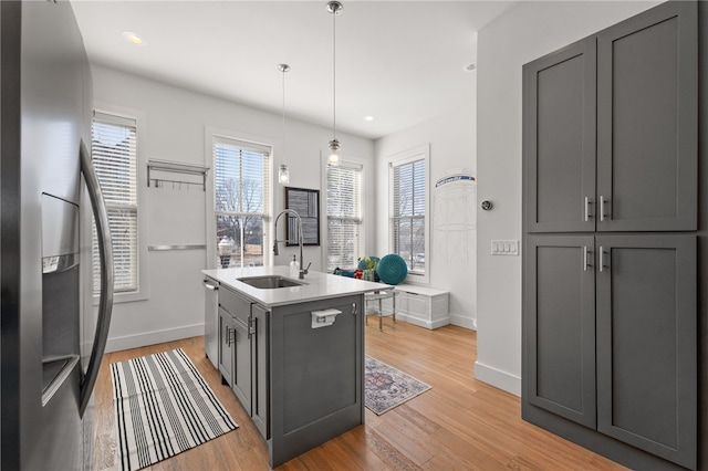 kitchen with light wood finished floors, light countertops, gray cabinetry, appliances with stainless steel finishes, and a sink