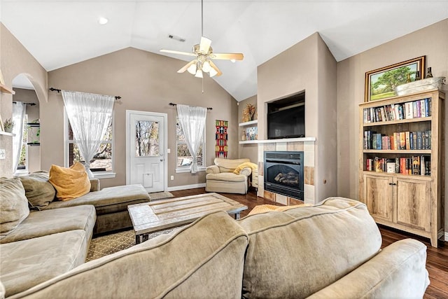 living room with vaulted ceiling, a tiled fireplace, ceiling fan, and dark hardwood / wood-style floors