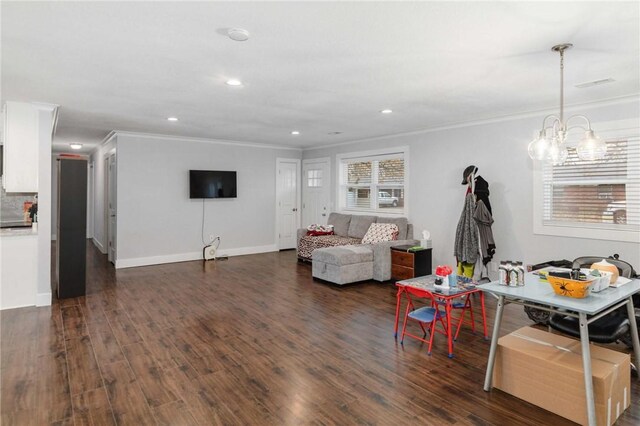 living room featuring dark hardwood / wood-style flooring, a notable chandelier, and ornamental molding