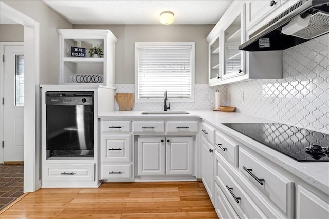 kitchen with decorative backsplash, light wood-type flooring, sink, black appliances, and white cabinetry