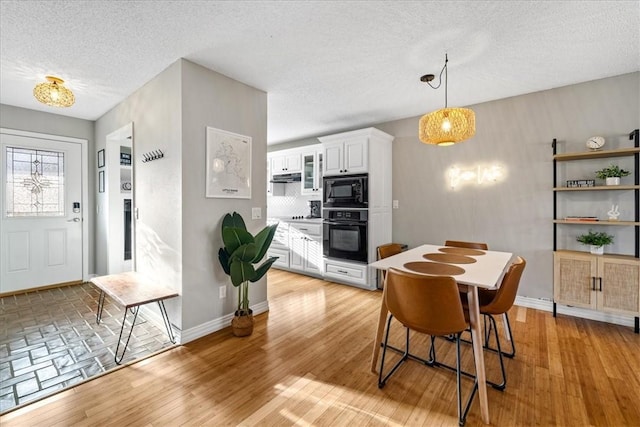 dining space with a textured ceiling and light hardwood / wood-style flooring