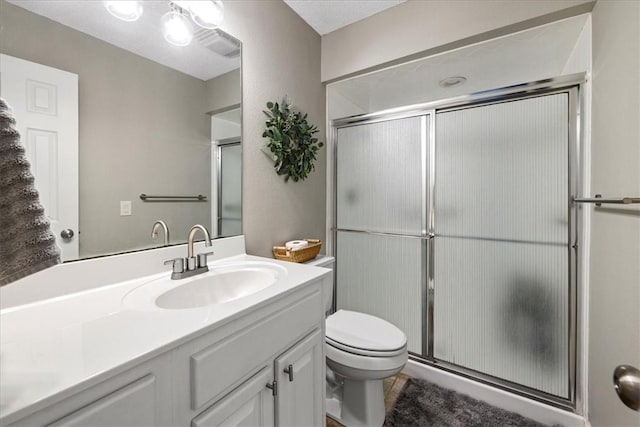 bathroom featuring vanity, toilet, and a shower with door