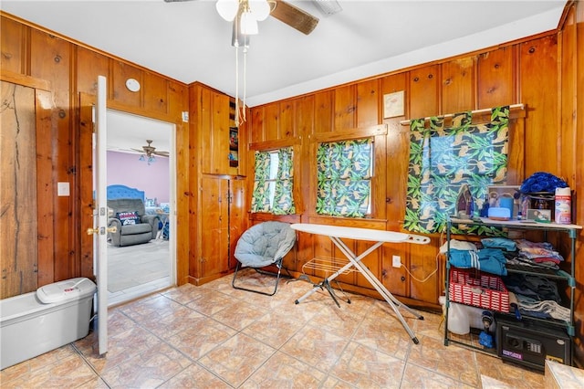 misc room featuring wood walls, ceiling fan, and light tile patterned flooring