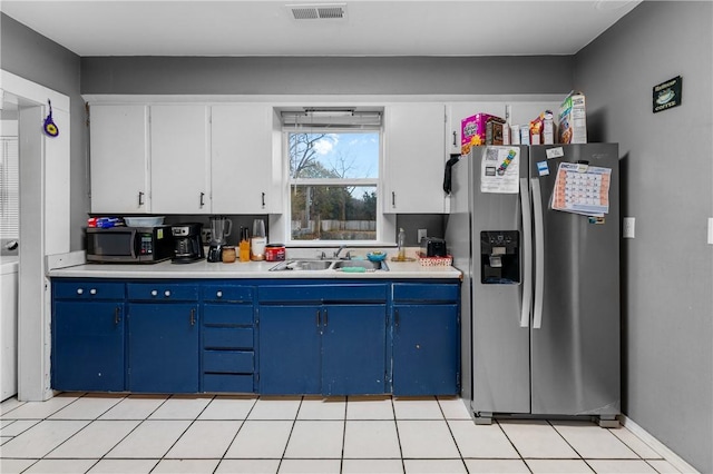 kitchen featuring blue cabinets, sink, light tile patterned floors, white cabinetry, and stainless steel appliances