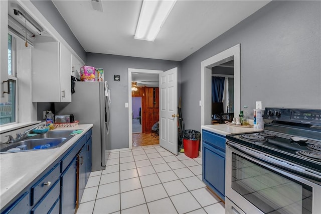 kitchen featuring sink, stainless steel appliances, white cabinets, blue cabinets, and light tile patterned flooring