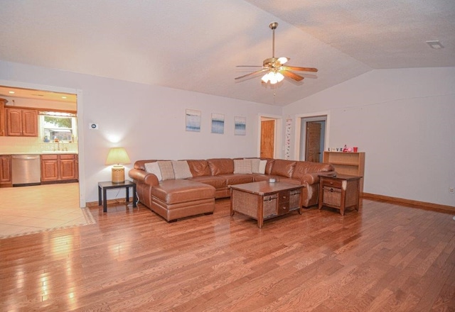 living room with ceiling fan, sink, vaulted ceiling, and light wood-type flooring