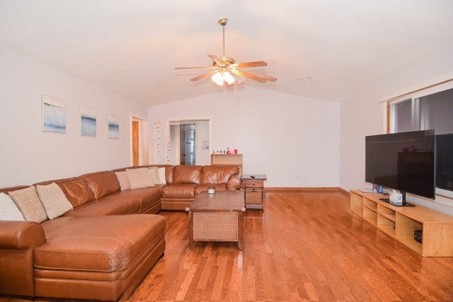 living room featuring ceiling fan, light wood-type flooring, and vaulted ceiling