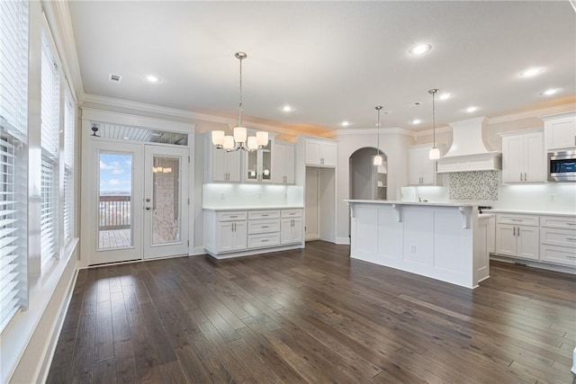 kitchen with white cabinets, decorative light fixtures, and premium range hood