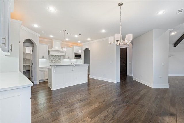 kitchen featuring pendant lighting, white cabinets, and premium range hood