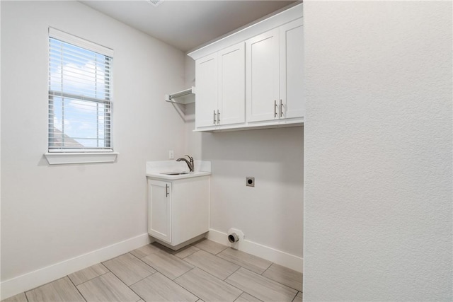 laundry room featuring sink, light hardwood / wood-style flooring, cabinets, and hookup for an electric dryer