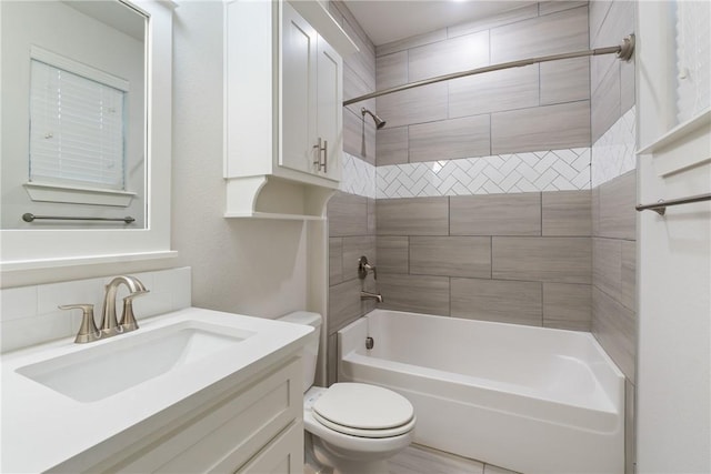 full bathroom featuring tiled shower / bath combo, toilet, and vanity