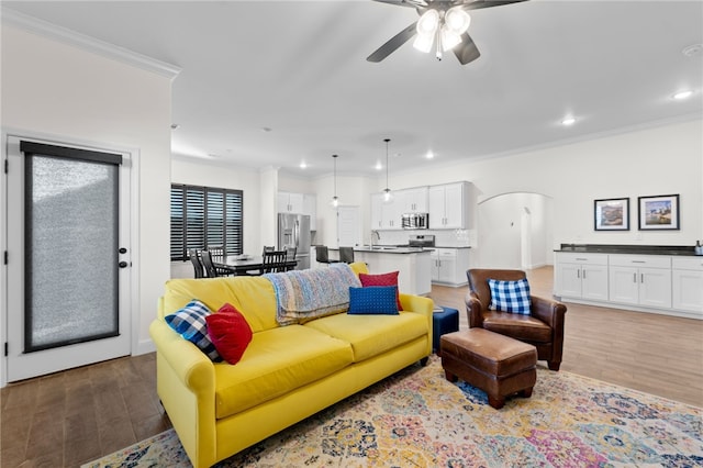 living room with hardwood / wood-style flooring, ceiling fan, ornamental molding, and sink