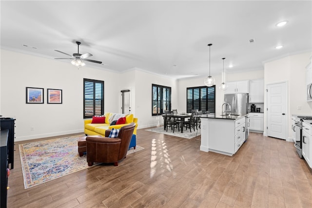 living room with ceiling fan, light hardwood / wood-style flooring, and ornamental molding