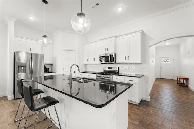 kitchen with white cabinets, an island with sink, appliances with stainless steel finishes, and dark wood-type flooring