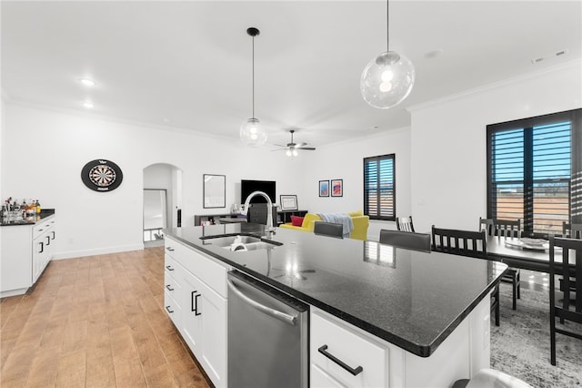 kitchen featuring stainless steel dishwasher, a kitchen island with sink, sink, light hardwood / wood-style floors, and hanging light fixtures