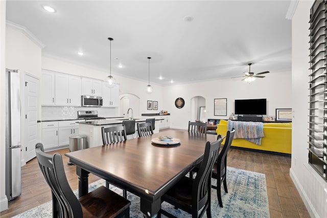 dining area with ceiling fan, hardwood / wood-style floors, sink, and ornamental molding