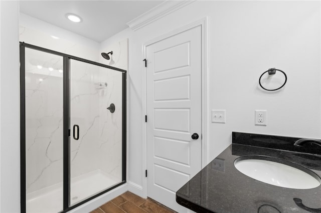 bathroom with hardwood / wood-style flooring, an enclosed shower, and sink