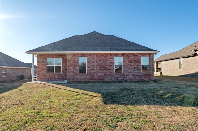 rear view of property featuring a lawn and central AC unit