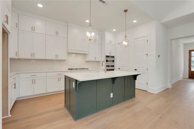 kitchen with light countertops, white cabinets, tasteful backsplash, and light wood finished floors