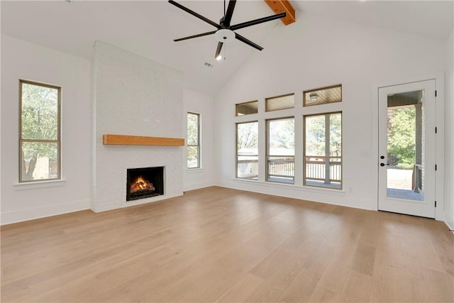 unfurnished living room featuring plenty of natural light, high vaulted ceiling, beam ceiling, and light wood-style flooring