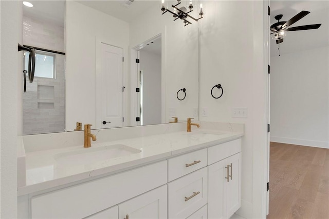 full bath with a sink, baseboards, wood finished floors, and double vanity