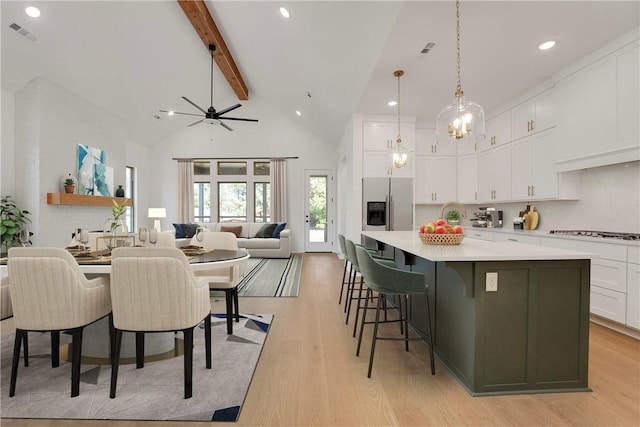 kitchen featuring visible vents, beamed ceiling, stainless steel refrigerator with ice dispenser, and white cabinetry