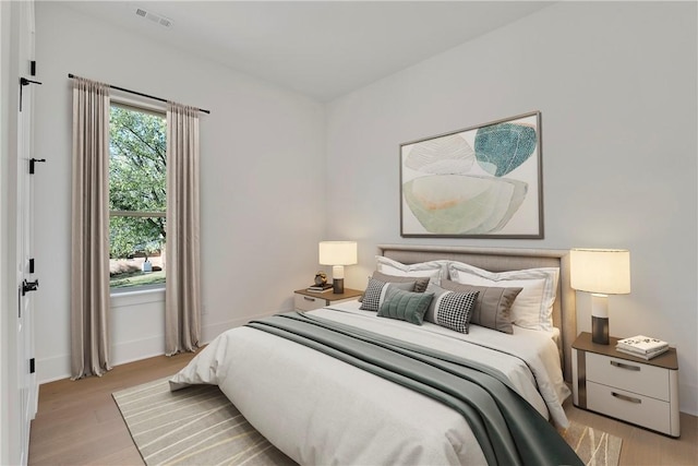 bedroom featuring visible vents, baseboards, and light wood-style floors