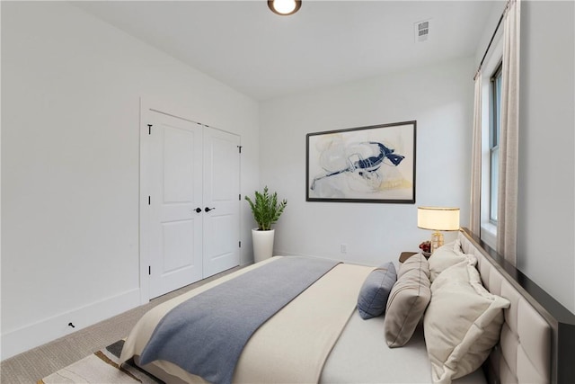 bedroom featuring a closet, carpet floors, baseboards, and visible vents