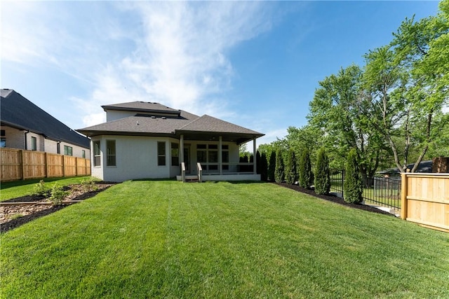 back of property with a lawn, a fenced backyard, stucco siding, and a sunroom