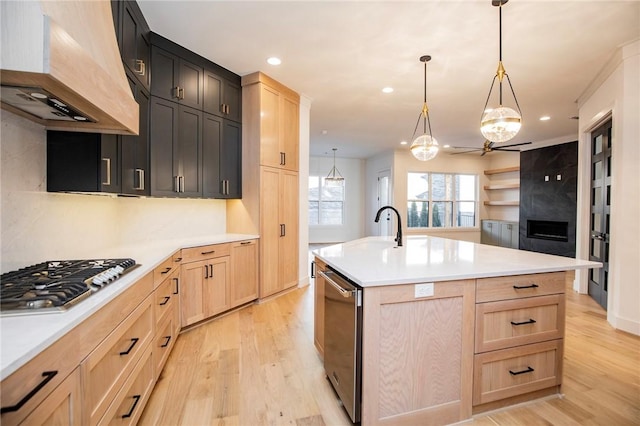 kitchen featuring pendant lighting, light brown cabinets, an island with sink, custom range hood, and stainless steel gas cooktop