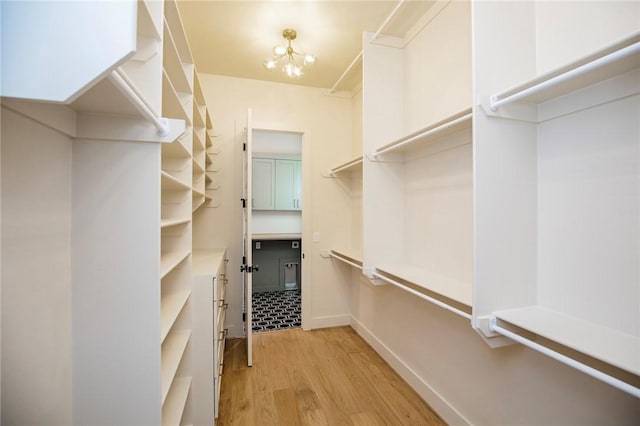 walk in closet featuring a chandelier and light wood-type flooring