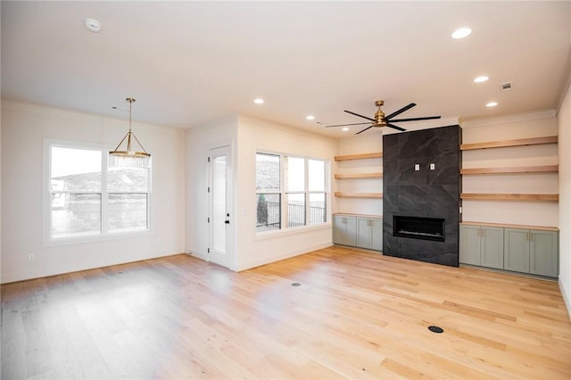 unfurnished living room with a fireplace, light wood-type flooring, ceiling fan, and ornamental molding