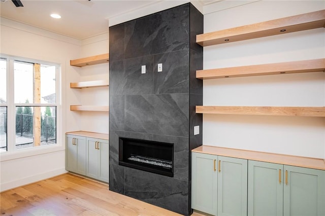 kitchen featuring plenty of natural light, crown molding, light wood-type flooring, and a fireplace