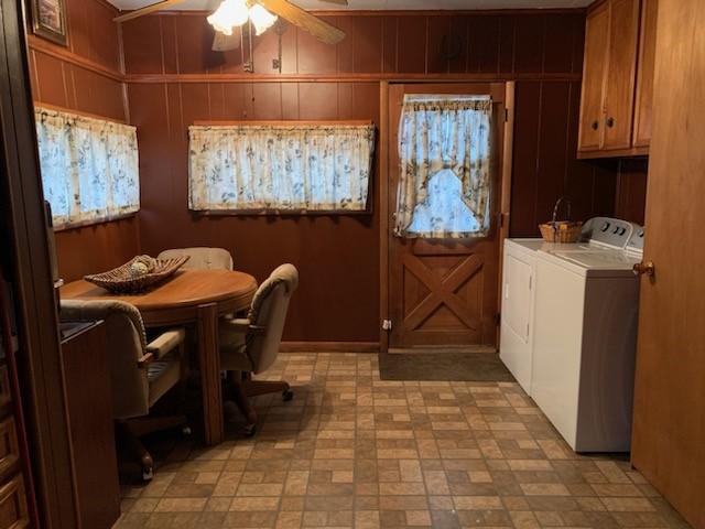 dining area with washing machine and dryer, ceiling fan, and wood walls