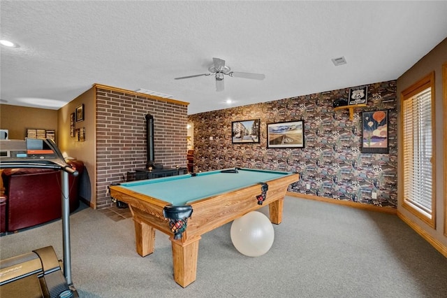 15262 Shipe Rd, Gravette, AR 72736 - playroom with ceiling fan, a wood stove, baseboards, carpet floors, and a textured ceiling