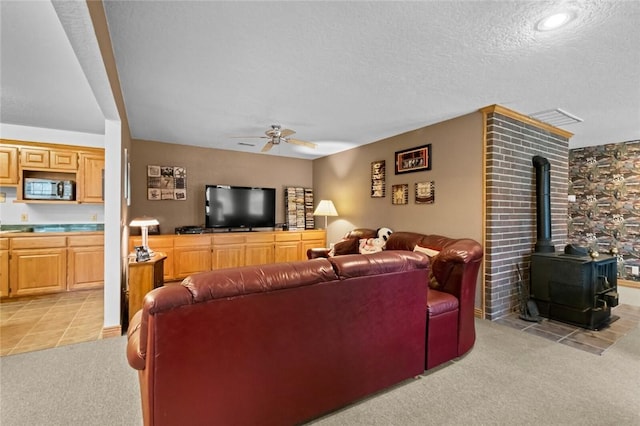 carpeted living room with a wood stove, ceiling fan, and a textured ceiling