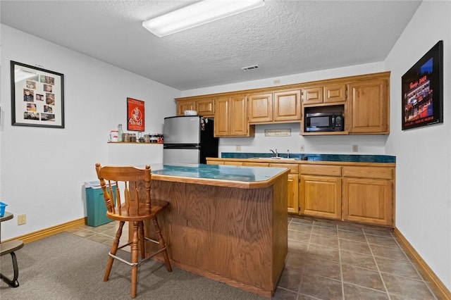 15262 Shipe Rd, Gravette, AR 72736 - kitchen with freestanding refrigerator, black microwave, a breakfast bar, a sink, and a textured ceiling