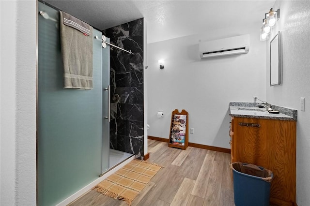 bathroom with a wall mounted AC, vanity, wood-type flooring, and tiled shower