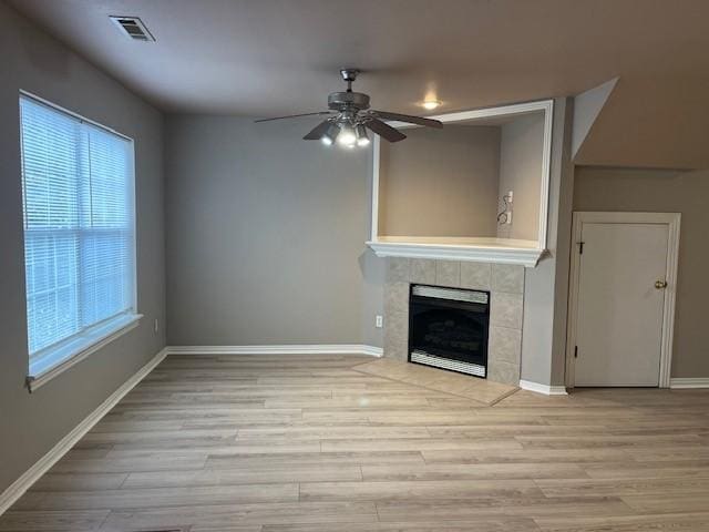 unfurnished living room featuring a tile fireplace, ceiling fan, and light hardwood / wood-style flooring