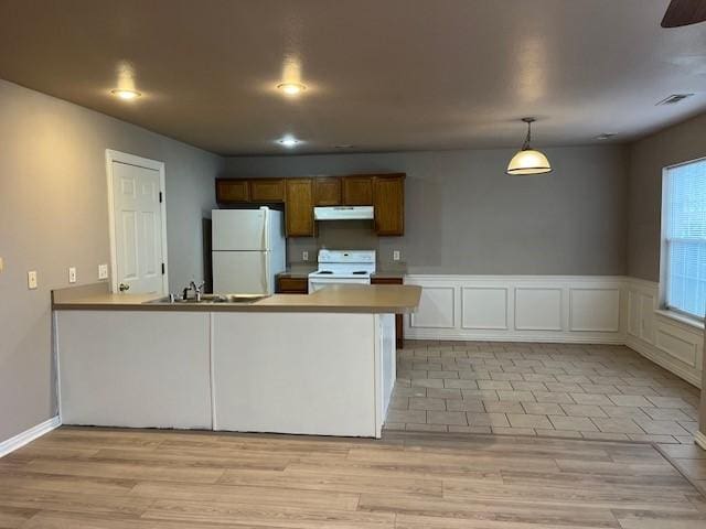 kitchen featuring sink, hanging light fixtures, kitchen peninsula, light hardwood / wood-style floors, and white appliances