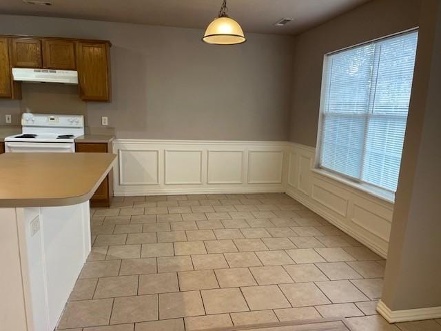 kitchen with hanging light fixtures, white electric range oven, light tile patterned flooring, kitchen peninsula, and a breakfast bar area