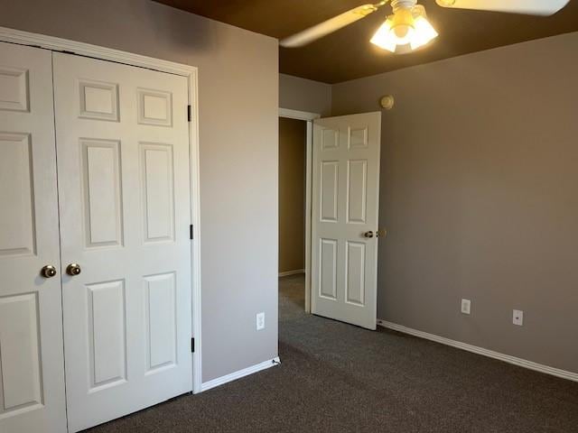 unfurnished bedroom with ceiling fan, a closet, and dark colored carpet