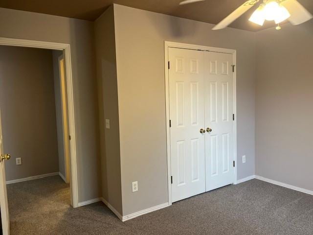 unfurnished bedroom featuring dark colored carpet, ceiling fan, and a closet