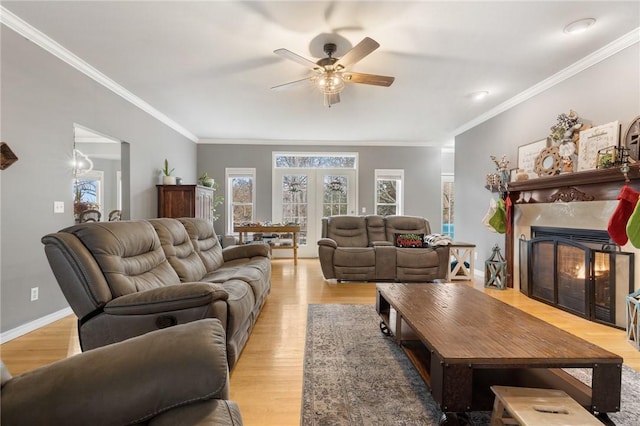 living room with light wood-type flooring, ceiling fan, crown molding, and a premium fireplace