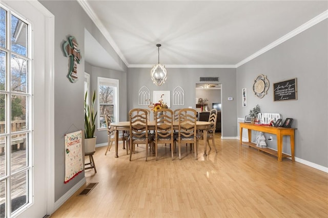 dining area featuring a chandelier, light wood-type flooring, and crown molding