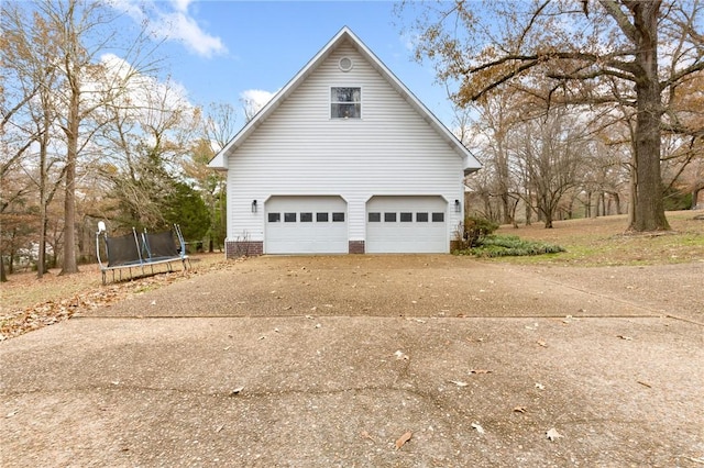 view of property exterior with a trampoline and a garage